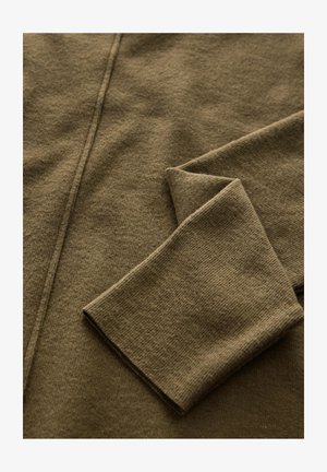 Brown knitted fabric with a smooth texture; features a folded sleeve and a subtle pattern. Soft, thick material with neat stitching.