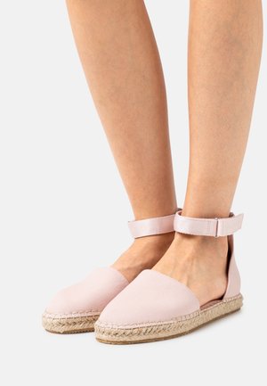 Jasnoróżowe espadryle z płóciennym wierzchem, jutową podeszwą i paskiem na kostce. Charakteryzują się okrągłym noskiem i otwartym designem pięty.