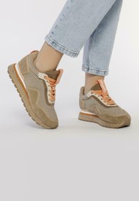 Zapatillas de malla y ante beige con cordones y acentos naranjas. Presentan una entresuela texturizada y suela de goma para mayor agarre.
