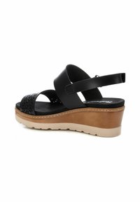 Sandalias de cuña negras con una correa perforada, material de cuero, plantilla contorneada y una suela de goma de color claro.
