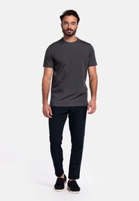 Grijze korte mouwen t-shirt, zachte stof, ronde halslijn, gecombineerd met donkere broeken en zwarte instappers. Eenvoudige, moderne pasvorm.