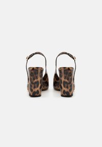 Blokkhælede sandaler med blank leopardprint, åben ryg og ankelrem med guldspænde. Glat tekstur, rund tå.