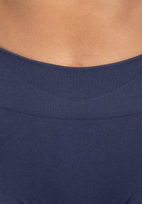 Cintura de tela acanalada en azul marino de indumentaria atlética, que presenta una textura suave y un diseño ajustado, que complementa el tono de piel.