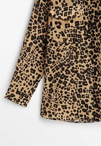 Chemise à manches longues avec un motif léopard noir et fauve, dotée d'une poche poitrine simple avec rabat.