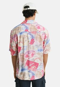 Korte mouwen shirt in lichte pastelkleuren met een tropische print, inclusief palmbomen en strandmotieven, gemaakt van een lichtgewicht stof.
