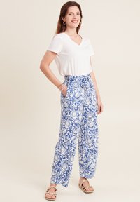 Witte v-hals t-shirt gecombineerd met blauw-witte bloemenpatroon wijde broek, met een strik taille en een losse pasvorm.