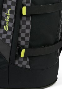 Schwarzer Rucksack mit kariertem Muster, der gelbe Akzente, mehrere Riemen und eine texturierte Oberfläche für Haltbarkeit aufweist.