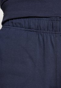 Cintura elástica de color azul marino con textura recogida, combinada con una textura de tela suave en el mismo color, adecuada para uso casual.