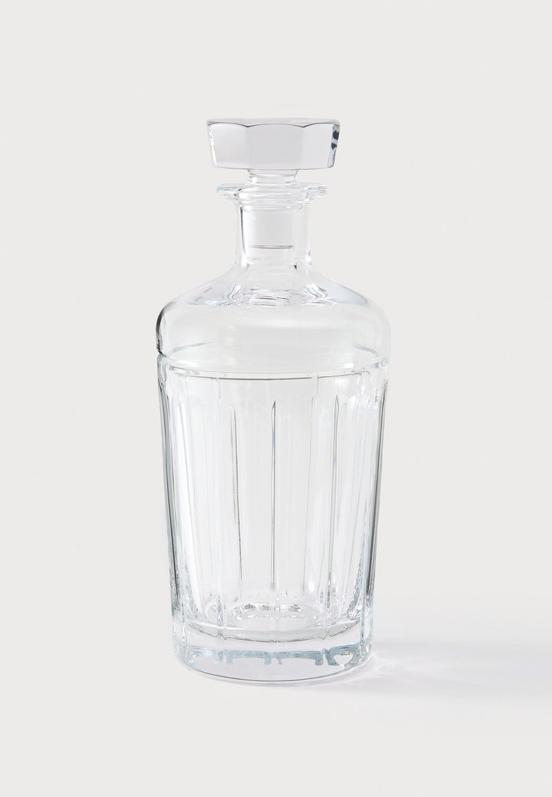 Klare Glasdekantier mit vertikal geriffeltem Design, einem sechseckigen Stopfen und einem glatten zylindrischen Hals. Reflektiert Licht und zeigt Klarheit.