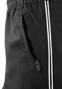 Schwarze Sportsch shorts mit elastischem Bund, seitlichen Reißverschlusstaschen und weißen Streifen entlang der Kanten. Glatte Stoffoberfläche.