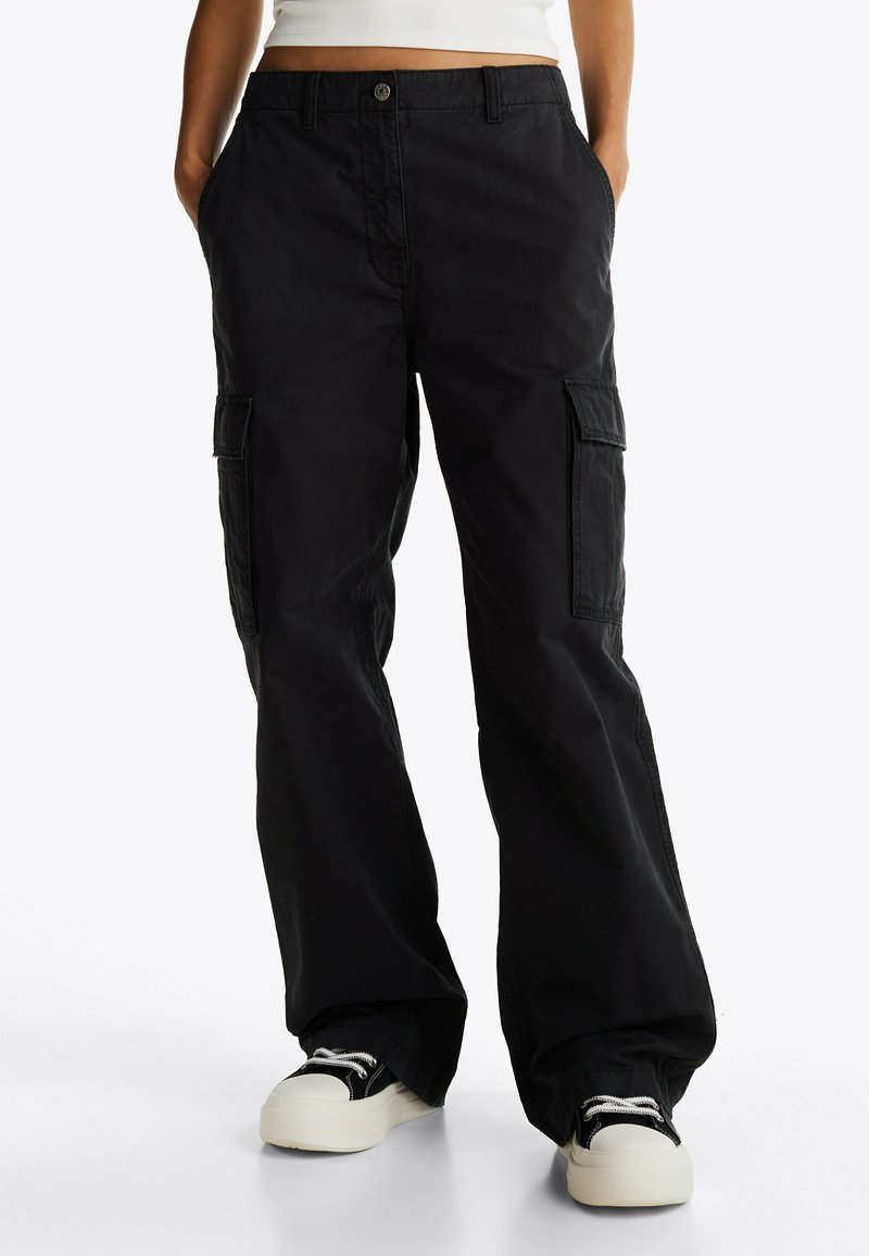 Pantalones cargo negros de corte holgado, con grandes bolsillos laterales y cierre de botón. Fabricados en una tela ligera con una textura suave.