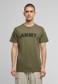 Olivinės spalvos medvilnės marškinėliai, trumpomis rankovėmis ir apvaliu iškirpimu, su ryškiu juodu užrašu "ARMY" krūtinėje.