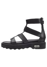 Sandali in pelle nera con molte cinghie incrociate, suola spessa e zip laterale, caratterizzati da un motivo testurizzato e un accento con logo argentato.