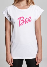 Witte korte mouw t-shirt van katoen, met een gedurfde roze cursieve "Bae" grafiek op de voorkant, met een losse, casual pasvorm.