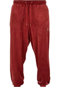 Red velvet joggers with an elastic waistband, drawstring accents, and cuffed hems. Features a small logo on the side. Soft texture.