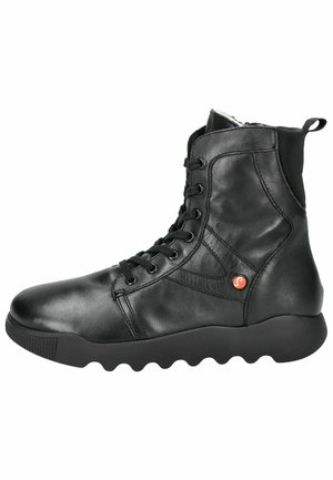 Botas de tobillo de cuero negro con puntera redonda, parte delantera con cordones y suela de goma texturizada, con un acento de logo rojo en el lateral.