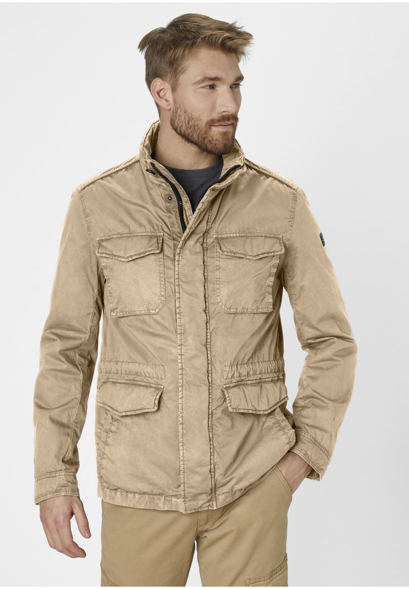 Beige utility jacket made of lightweight fabric, featuring two chest pockets, an adjustable collar, and a cinched waist for a fitted look.