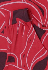 Tissu rouge avec un motif floral abstrait rose et violet foncé, présentant un détail de couture froncée et un col rond.