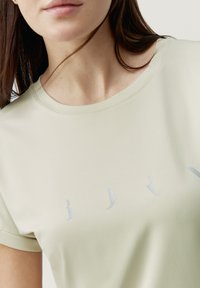 Lichtgroen t-shirt met korte mouwen, gemaakt van gladde, zachte stof, met een subtiel logoontwerp in een iets donkerdere tint aan de voorkant.