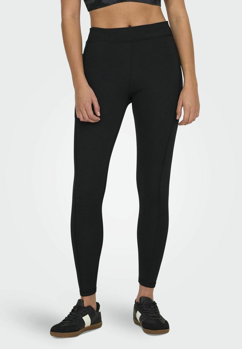 Zwarte leggings gemaakt van rekbaar materiaal met een hoge tailleband, voorzien van een gladde textuur en zijnaad voor een gestroomlijnde pasvorm.