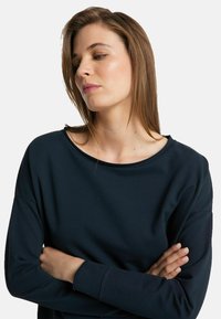 Navy blue sweatshirt with a wide neckline, long sleeves, and a relaxed fit. Made of soft fabric, featuring minimal stitching and no patterns.