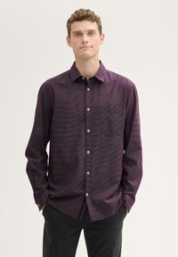 Long-sleeve, button-up shirt in a textured purple fabric with a subtle pattern. Features a single chest pocket and white buttons.