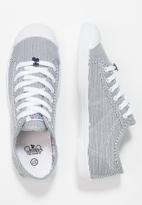 Sneakers in tela con strisce verticali blu e bianche, suole in gomma bianca e lacci. Presentano un piccolo logo vicino ai fori per i lacci.