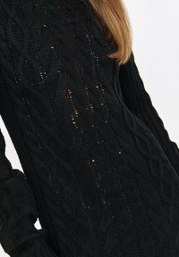 Czarny sweter z dzianiny z okrągłym splotem, z prążkowanym dekoltem i mankietami, wykonany z miękkiej, teksturowanej przędzy.