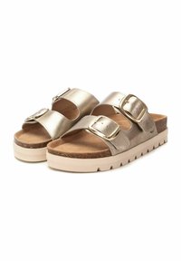 Chanclas metálicas doradas con dos hebillas ajustables, plantilla de corcho y una suela gruesa de color crema con una base texturizada.