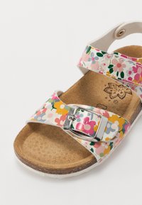 Floral-patterned sandal with two adjustable straps, silver buckle, cork footbed, and textured tan insole. White rubber sole.