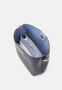 Granatowa skórzana torba o miękkiej fakturze, niebieskie podszewki, komora na zamek oraz akcenty w kolorze złotym. Wnętrze zawiera organizer kieszeni.