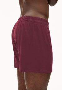 Shorts in cotone borgogna con vita elasticizzata, caratterizzati da una texture liscia e una vestibilità comoda, vista ravvicinata dal retro.