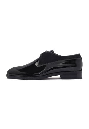 Chaussures en cuir verni noir avec une finition lisse, des accents en suede et un bout arrondi. Le design présente un petit talon empilé.