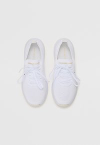 White athletic shoes with mesh upper, round toe, and flat laces. Features subtle branding in gold on the tongue. Textured sole for grip.