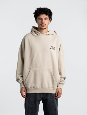 Sweat à capuche beige en tissu doux, avec une poche avant et un petit logo sur la poitrine, doté de manches amples.