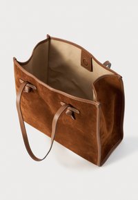 Sac tote en suède marron avec des poignées en cuir. Le design à ouverture supérieure révèle un intérieur en tissu beige et un petit détail de fermeture à bouton.