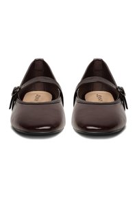 Zapatos de cuero marrón con punta en forma de almendra, que incluyen una correa única con una hebilla decorativa y una suela texturizada.
