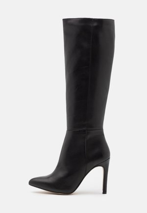Czarny sięgający do kolan skórzany botek z ostrym noskiem i wysokim obcasem na szpilce, gładka faktura i minimalistyczne przeszycia.