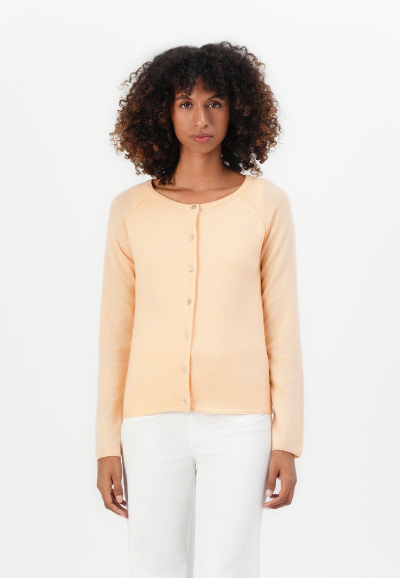 Cardigan u breskvastoj boji s gumbima, raglan rukavima, mekim materijalom, okruglim izrezom i jednostavnim prednjim zakopčanjem. Slim fit dizajn.
