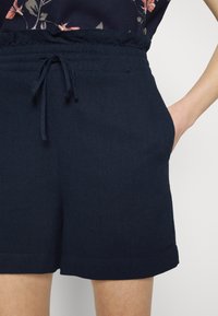 Shorts blu navy realizzati in tessuto morbido, dotati di una vita elastica con cordino, tasche laterali e una vestibilità casual dritta.