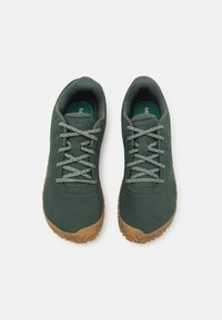 Scarpe verde scuro con tomaia in pelle liscia, lacci grigi textured e suola in gomma tan a contrasto. Presentano un design a collo basso per un facile utilizzo.
