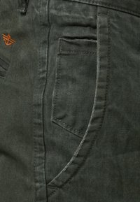 Ciemnozielone spodnie dżinsowe z teksturowanej tkaniny, z przednią kieszenią, szczegółowym przeszyciem oraz wyszywanym logo na pasku talii.