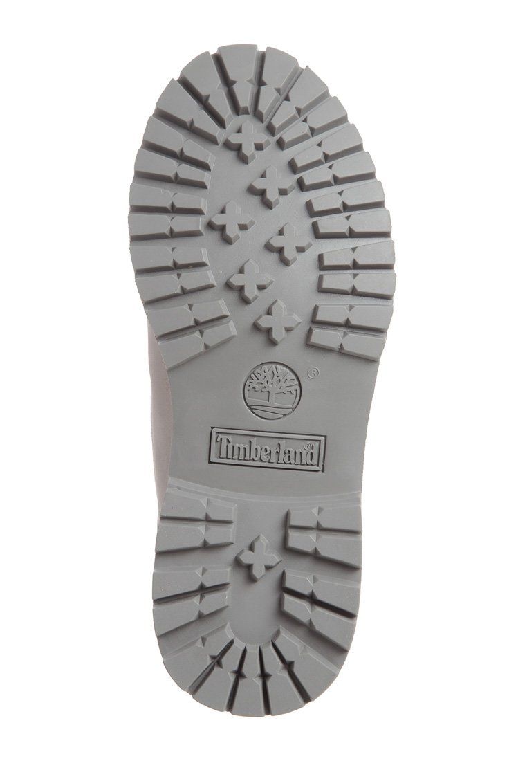 Semelle en caoutchouc grise avec un design de semelle robuste, arborant un logo central et plusieurs motifs en relief pour l'adhérence et la durabilité.