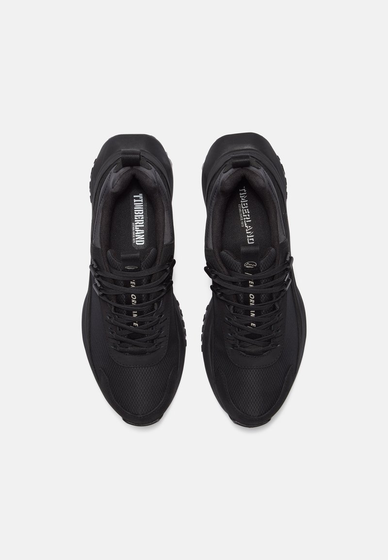 Zapatillas deportivas negras con una parte superior de malla texturizada. Presenta cordones negros, puntera reforzada y un logotipo de la marca en la lengüeta. Suela de goma.