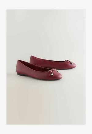Baleríny v tmavoburgundskej koži, zaoblený špičkou, s malou mašľou a kovovými akcentmi. Plochá podrážka pre každodenné nosenie.