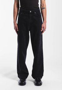 Musta leveälahkeiset farkut, valmistettu denimistä, joissa on korkea vyötärö, viisi taskua ja napillinen kiinnitys. Sileä pinta ja hienovaraiset ompeludet.