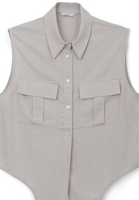 Camicetta senza maniche beige con colletto a punta e due tasche con patta sul petto, esposta piatta su uno sfondo bianco.