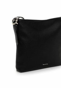 Sac à main en cuir noir avec une texture granuleuse, accents en métal argenté, forme élancée et fermeture éclair. Logo embossé près du bas.