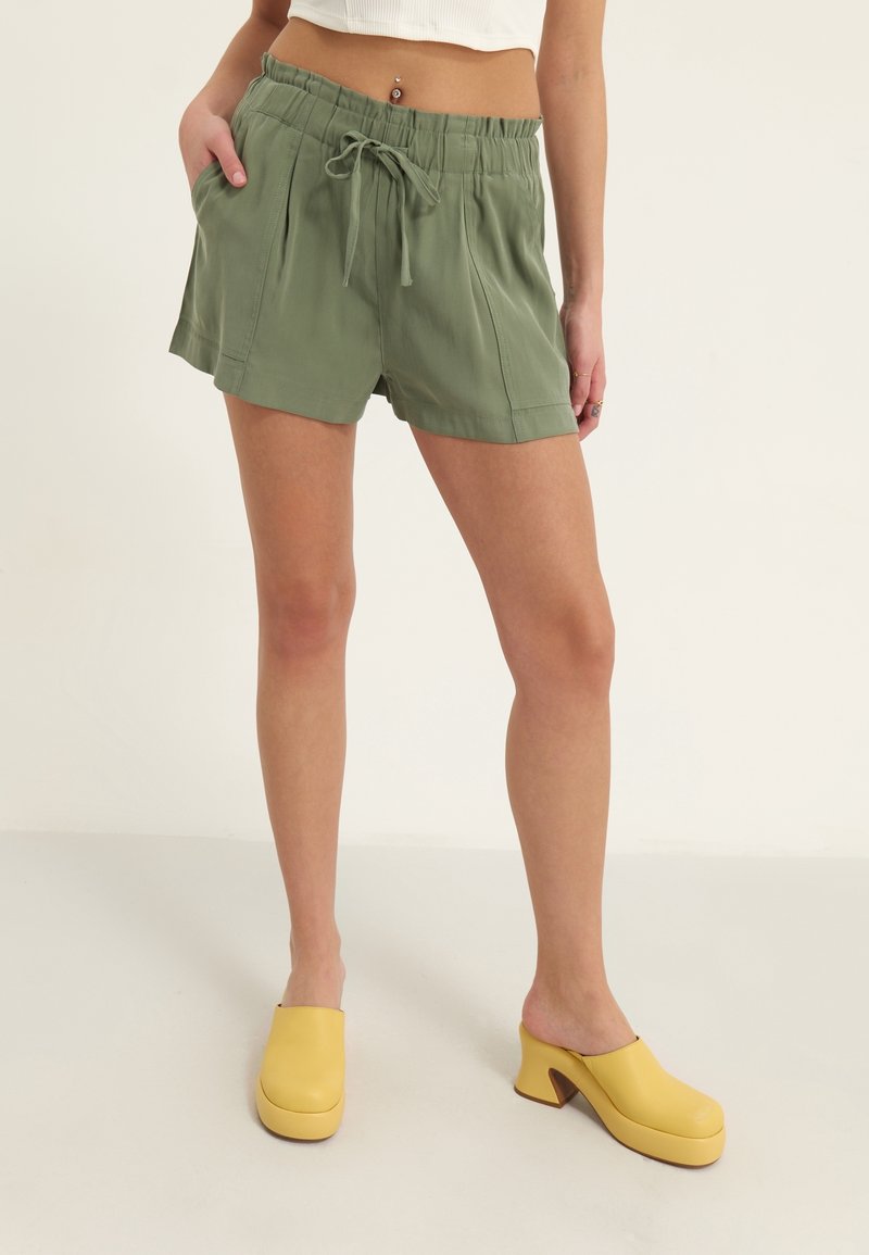 Groene, lichtgewicht stoffen korte broek met een ontspannen pasvorm, elastische tailleband en trekkoord. Gecombineerd met gele plateausabots.