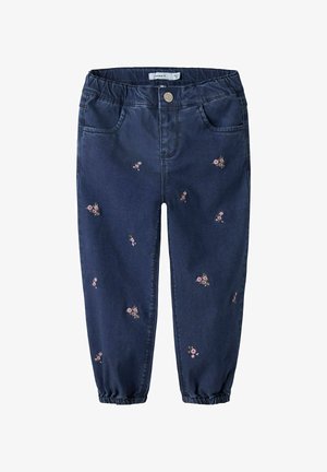 Tumedat sinise denimi püksid, millel on tikitud lillemotiivid, elastsest materjalist vöökoht ja elastsed mansetid pahkluude juures. Viie taskuga disain.